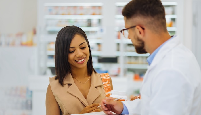 Smiling pharmacist assisting a customer with a product consultation in a bright pharmacy setting