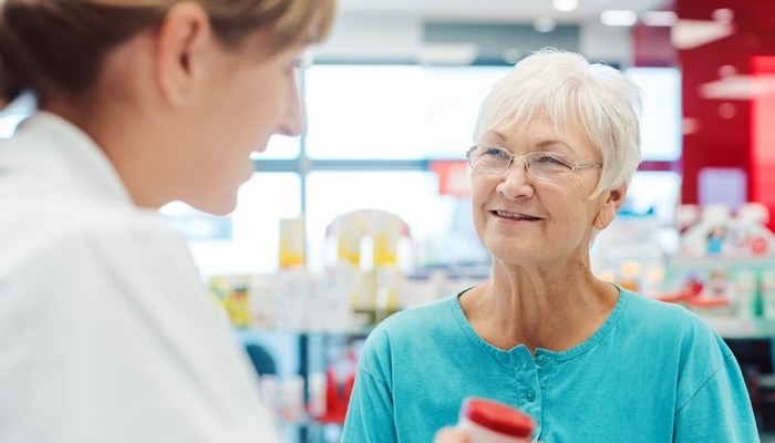 A pharmacist engaging in a cheerful conversation with an older customer in a pharmacy