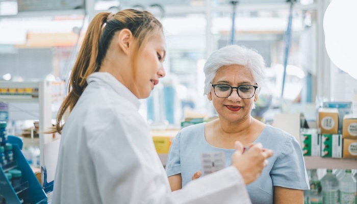 Pharmacist showing senior lady medicines